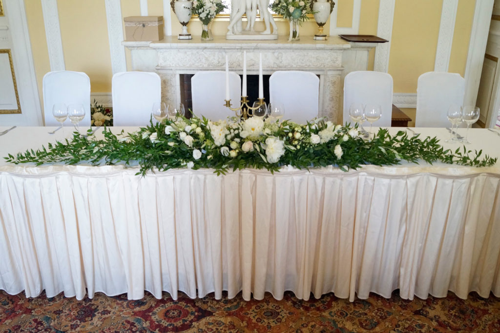 duża girlanda z zieleni i kwiatów jako dekoracja stołu pary młodej