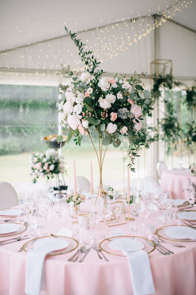 zwiewna aranżacja kwiatowa z białych i jasnoróżowych kwiatów jako dekoracja stołów gości