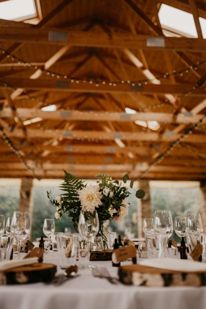 bukiet z paproci i dalii na drewnianym plastrze jako główna dekoracja stołu na przyjęcie weselne