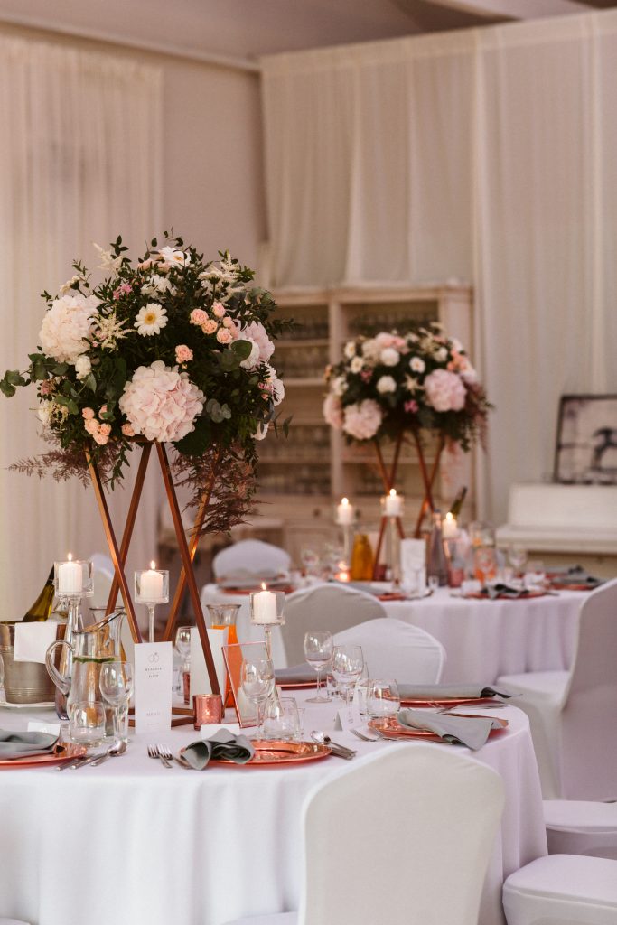 miedziane i szare dodatki dekoracyjne na stołach gości oraz dużo świec w klasycznym stylu
