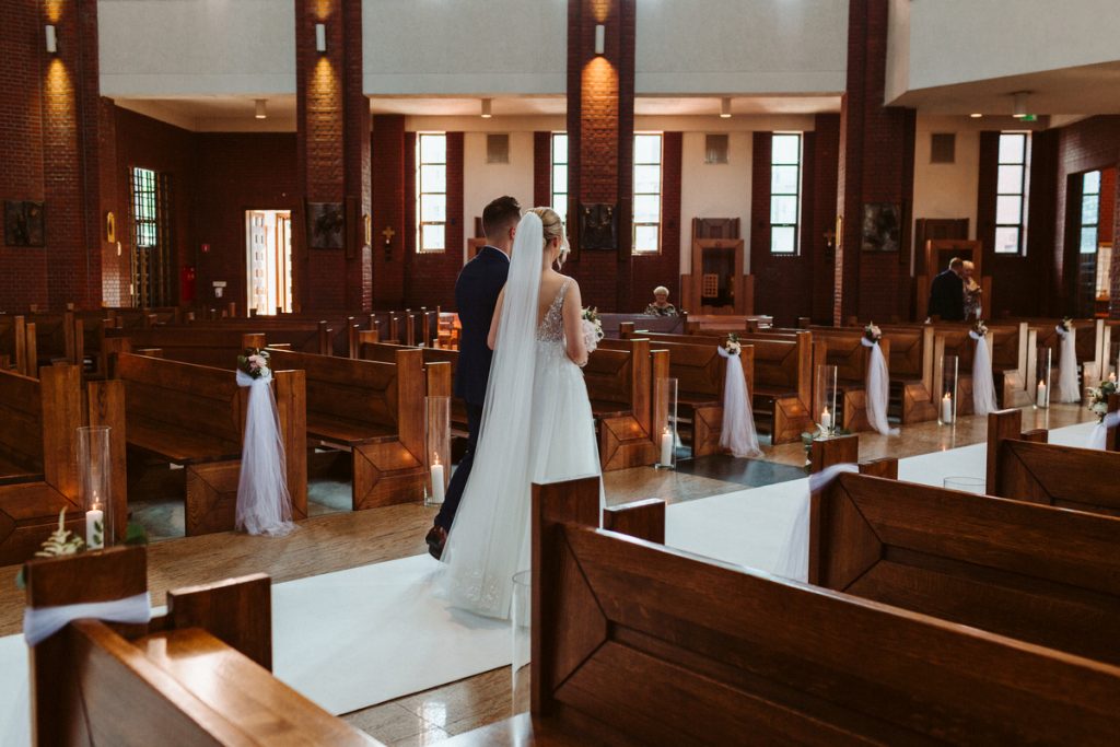 para młoda wychodząca z kościoła udekorowanego do ślubu białym dywanem i tiulem