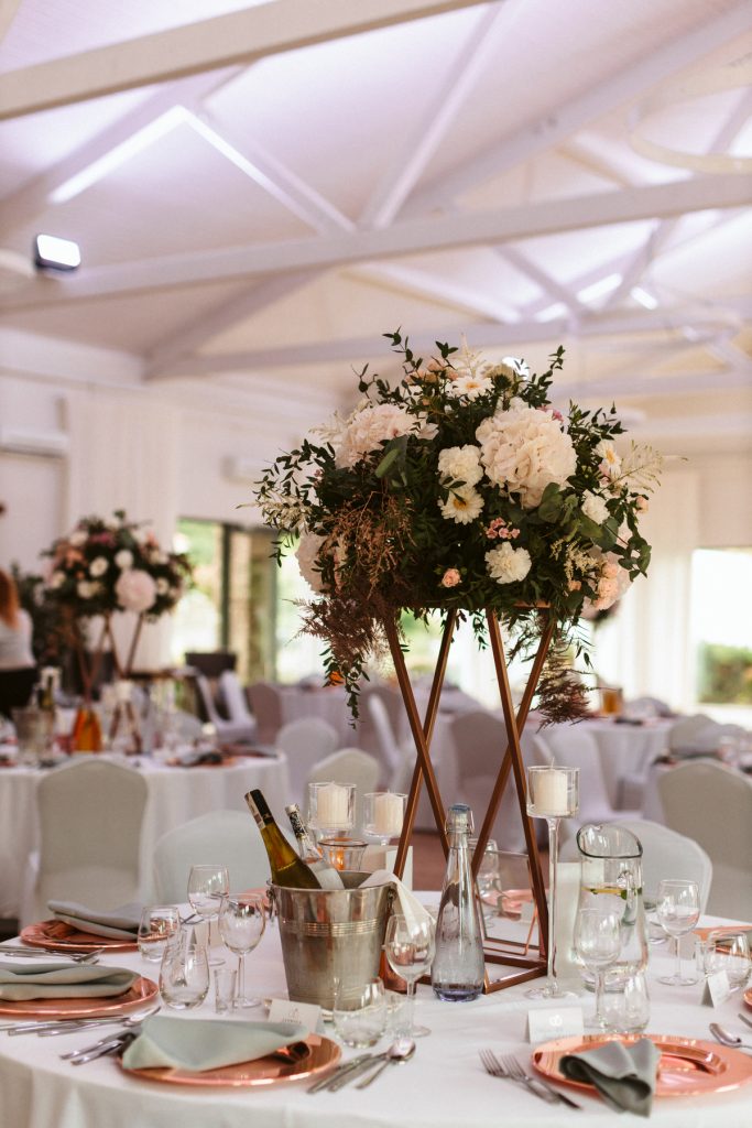 kompozycje kwiatowe kuliste z dodatkiem miedzianych liści jako dekoracja stołów gości w polo club