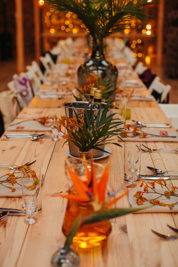 egzotyczne dodatki kwiatowe i zieleń jako dekoracja w wazonikach do dekoracji stołów weselnych