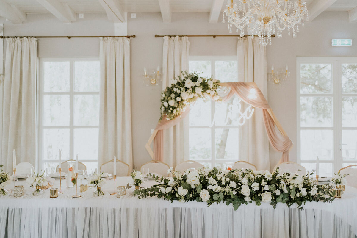 asymetryczna dekoracja stołu prezydialnego z białych kwiatów i zieleni w stylu bohoglam