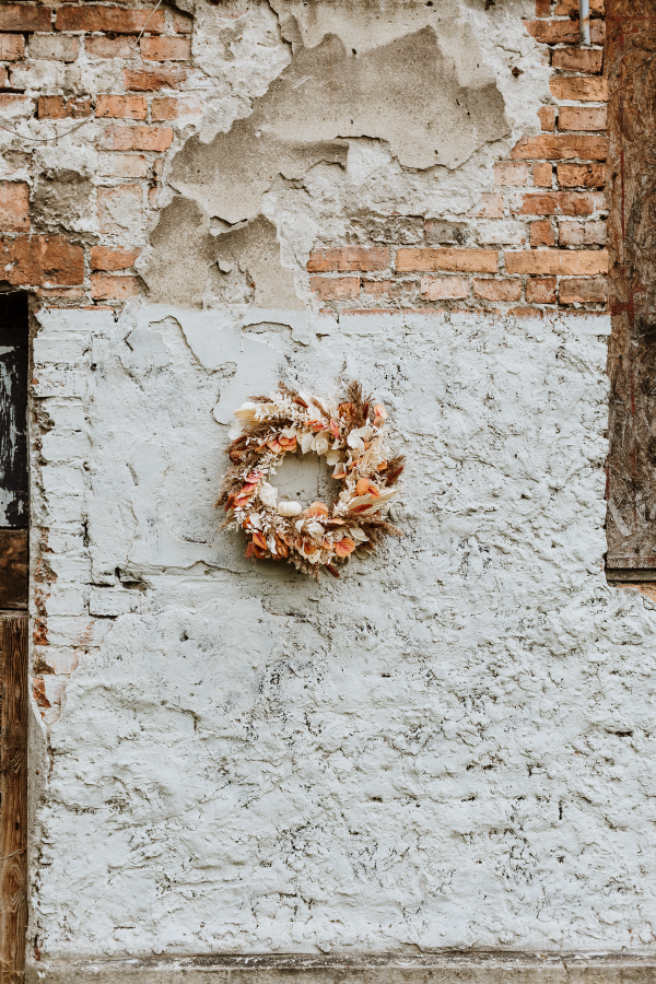 biały wianek z suszonych roślin na ścianę z cegły na jesienny sezon jako wystrój domu