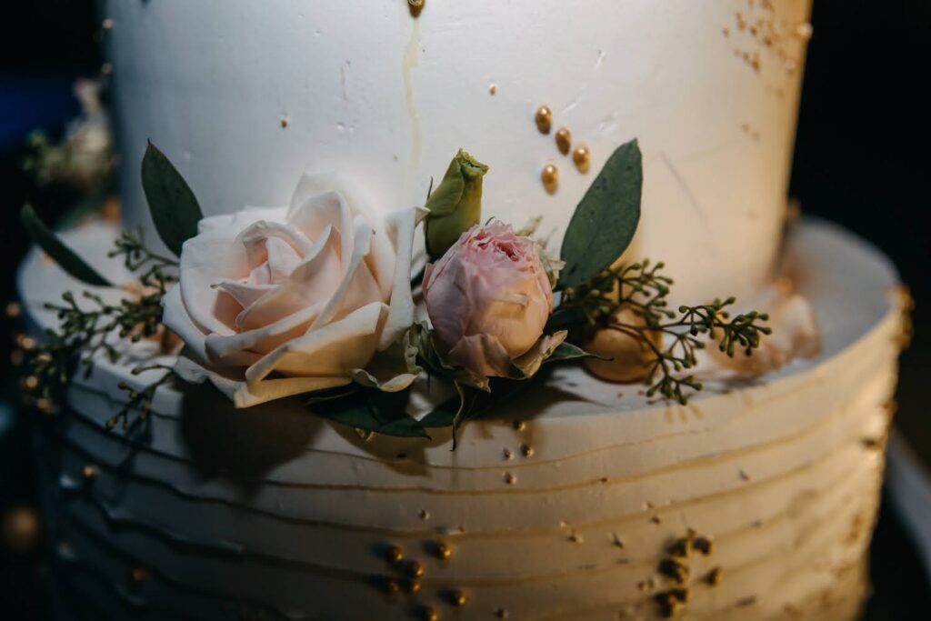 kwiaty świeże róże i eukaliptus jako dekoracja tortu na przyjęcie weselne